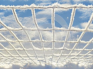 Fence covered with fine frost and snow crystals in morning sunlight