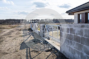 The fence in front of the house during construction made of brick, visible steel gate in a raw state.