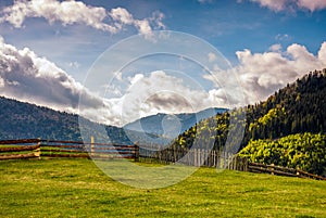 Fence through the grassy meadow in mountains