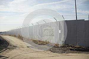 Fence in industrial zone. Road along territory. Passage between fences