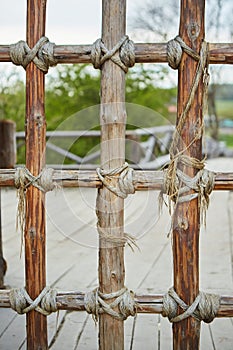 A fence made of thin wooden branches or logs tied with a rope.