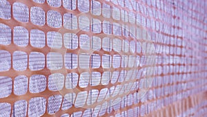 Fence with metal grid with white and orange plastic sheets