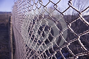 Fence of metal mesh covered with frost. The concept of incarceration behind a frozen metal mesh into custody. photo