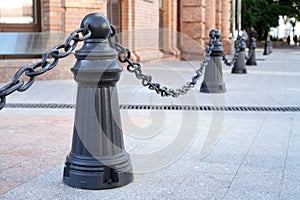 Fence of metal poles and chains on the street.