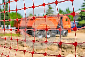 Fence net behind which is a truck at a construction site