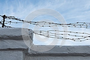 Fence with old barbed wire. Barbed wire against the blue sky. Rusty barbed wire.