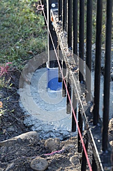 A fence panel has been added to a metal post set in concrete, pink builder\'s string has been run.