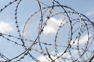 Fence with razor barbed wire protection against blue sky background. Dictatorship and tyranny concept photo