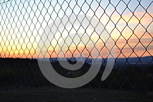 A fence showing a sunset photo