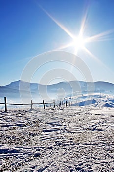 Fence in snow covered mountain under blue sky