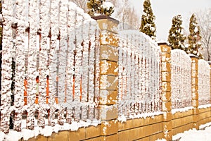 Fence in the snow in the winter afternoon in the park