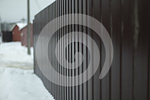 Fence in winter. Solid fence made of prof sheet. Steel brown prof sheet photo