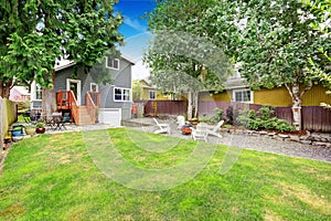 Fenced back yard with patio area and white adirondack chairs.