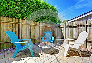 Fenced backyard with small patio area. Tile floor and green bushes