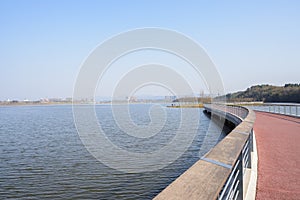 Fenced footbridge with red roadway over Lake Xinglong photo