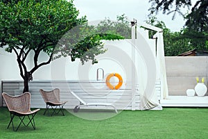Fenced yard with a beautiful white pool and a green lawn with chairs and sunbeds