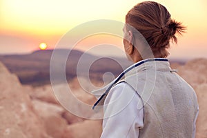 Fencer man on the rocky background and looking forward to the sun goes down