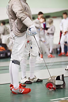 Fencer in white costume with rapier and protective mask on the floor
