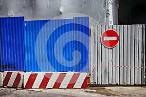 Fencing of construction site with red construction light on the background of blue profiled sheet fence and stop sign