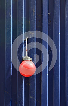 Fencing of construction site with red construction light on the background of blue profiled sheet fence