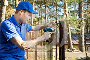 Fencing services - worker installing welded metal mesh fence