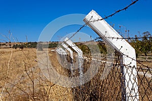 Fencing of white poles with barbed wire in the field