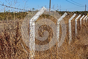 Fencing of white poles with barbed wire in the field