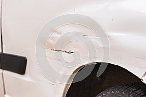 Fender damages, scratches and dents of white car after crash