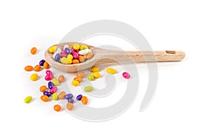 Fennel seed candy scattered around a wooden spoon isolated over white