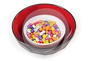 Fennel seed candy in a white red and black bowl isolated over white