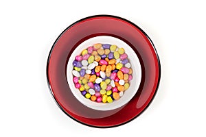 Fennel seed candy in a white red and black bowl isolated over white top down