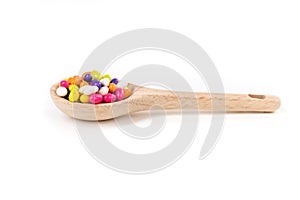 Fennel seed candy in a wooden spoon isolated over white