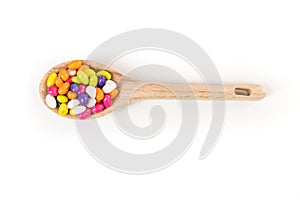 Fennel seed candy in a wooden spoon isolated over white top down