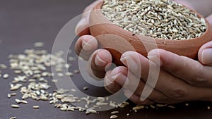 Fennel seeds in the clay bowl holding hands macro photography.