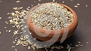 Fennel seeds in a small clay bowl on an old wooden table./ Fennel seeds over white background.