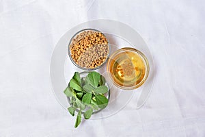 Fenugreek leaves with seeds and oil over white background. Concept of Indian ayurvedic medicine for blood suger, and damage hair