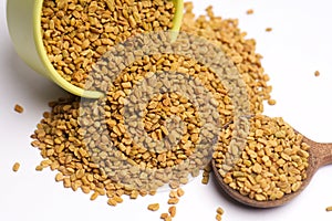 Fenugreek seeds with bowl in spoon on white background