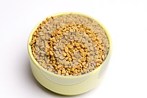 Fenugreek seeds in bowl on white background