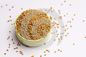 Fenugreek seeds with bowl on white background top angle