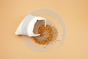 Fenugreek Seeds Methi Dana in white pouch on beige background. Shambhala or helba seeds is traditional Indian seasoning and