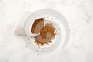 Fenugreek seeds spilled out of white pouch onto the surface of table. Shambhala or helba seeds is traditional Indian seasoning and