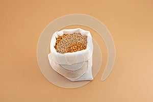 Fenugreek Seeds in white pouch on beige background. Shambhala or helba seeds is traditional Indian seasoning and ingredient