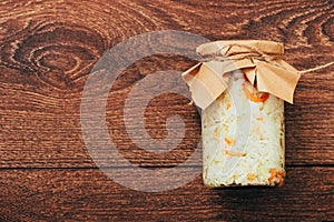 Fermented cabbage with carrot in a glass jar with closed paper from recycled materials on a wooden background. top view