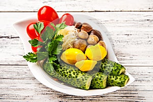 Fermented food on a white plate. Pickled tomatoes, cucumbers, sauerkraut, pickled champignon mushrooms closeup and copy space