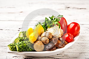 Fermented food on a white plate. Pickled tomatoes, cucumbers, sauerkraut, pickled champignon mushrooms closeup and copy space