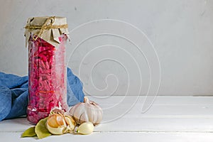 Fermented pickled vegetables. red cabbage with beets and bay leaves in a glass tall jar on a light background. copy space