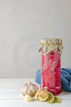 Fermented pickled vegetables. red cabbage with beets and bay leaves in a glass tall jar on a light background with copy space