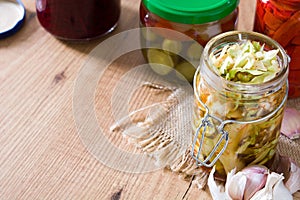 Fermented preserved vegetables in jar on wood