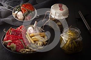 Fermented red and green hot peppers and garlic on a dark wooden table.