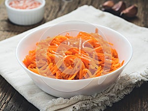 Fermented vegetables, Korean carrots. Asian spicy salad in white plate on wooden background